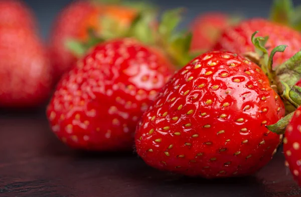 Fraises mûres rouges sur fond noir gros plan — Photo