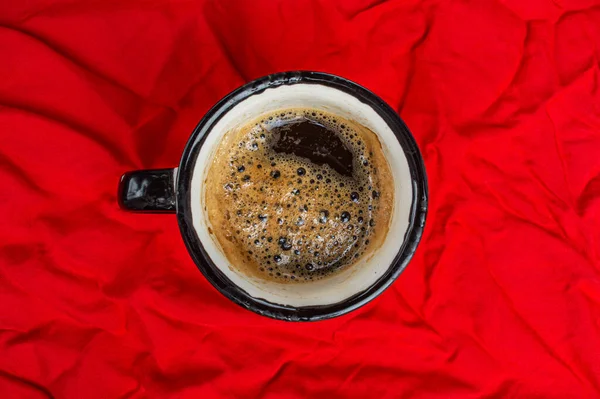 Чашка кофе на смятой красной ткани вид сверху крупным планом — стоковое фото