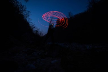 Açık havada karanlıkta ışıkla çiziyor.