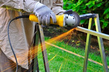 Metal kesmek için üçgen kullanan bilinmeyen bir adam..