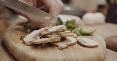 Ahşap mutfak tahtasında mantar ve yeşil biber doğruyorum.