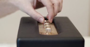 Bluetooth hoparlör ayarları ayarlanıyor - parmaklar modern bir bluetooth hoparlöründe ses ayarları için kontrol düğmelerini çeviriyor - trible, mids, bass