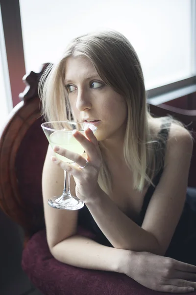 Blond kobieta w zielonej górze picia Martini — Zdjęcie stockowe