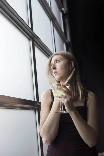 Mulher loira de vestido preto Bebendo um Martini — Fotografia de Stock