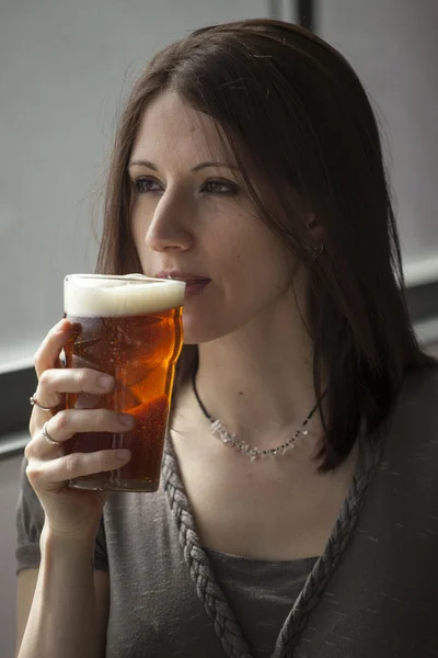 Красива молода жінка з коричневим волоссям п'є пінту — стокове фото