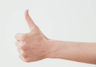 Beyaz arka planda baş parmağı havada bir kadın eli.