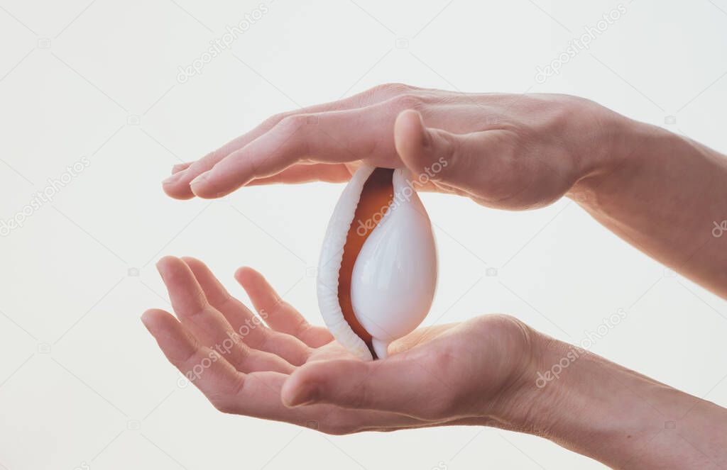 Woman holding a seashell against a white background. Close up