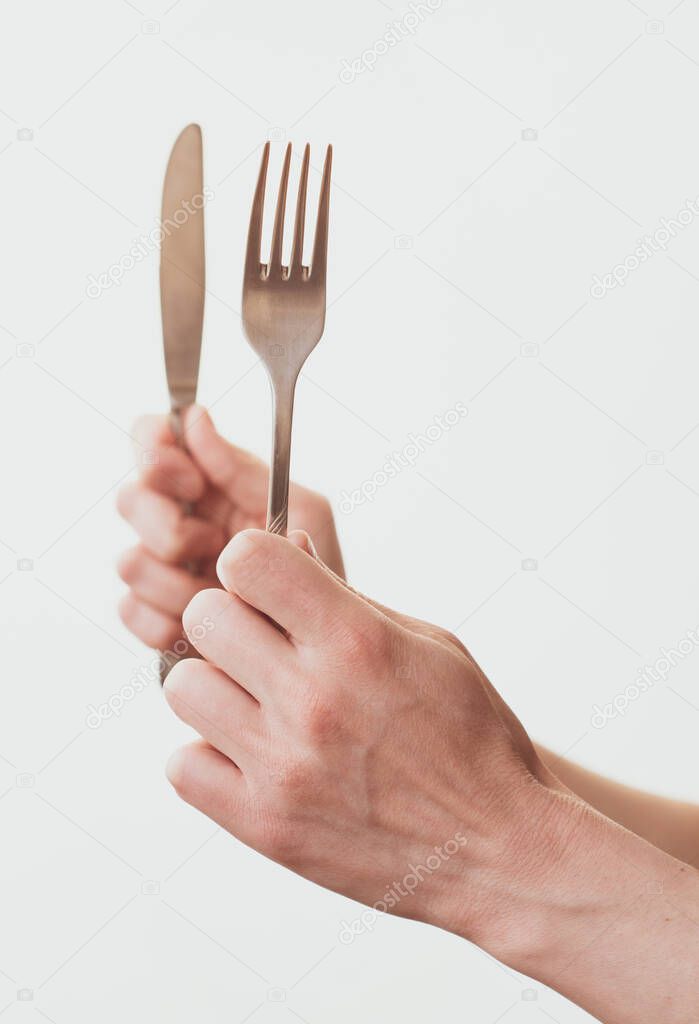 Woman hands holding a fork and a knife isolated on a white background