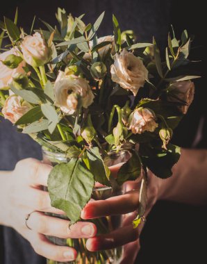 Bir buket çiçek tutan bir kadın. Güneşle aydınlatılan çiçekler..