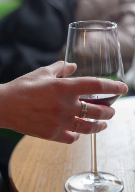 Kız elinde bir kadeh kırmızı şarap tutuyor.