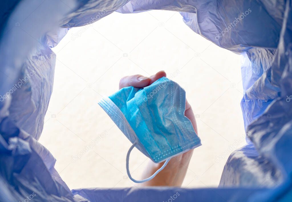 Throwing a face mask into the trash. With a  view from the inside of the trash bin.Post pandemic trash.