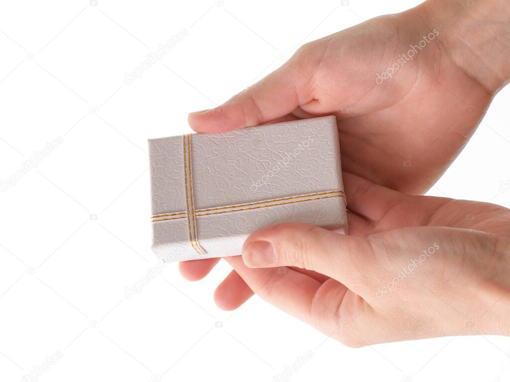 Female hands hold a small gift box on a white background.