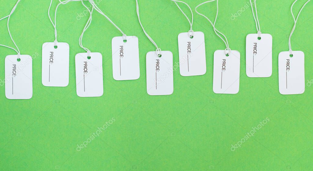 White price tags with copy space on a green background.Flat lay.
