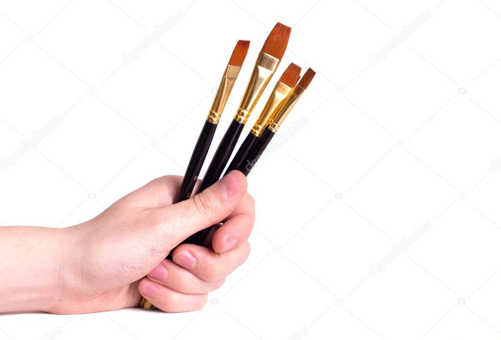 The artist's hand holds the paint brushes on a white background.Copy space. Close-up.