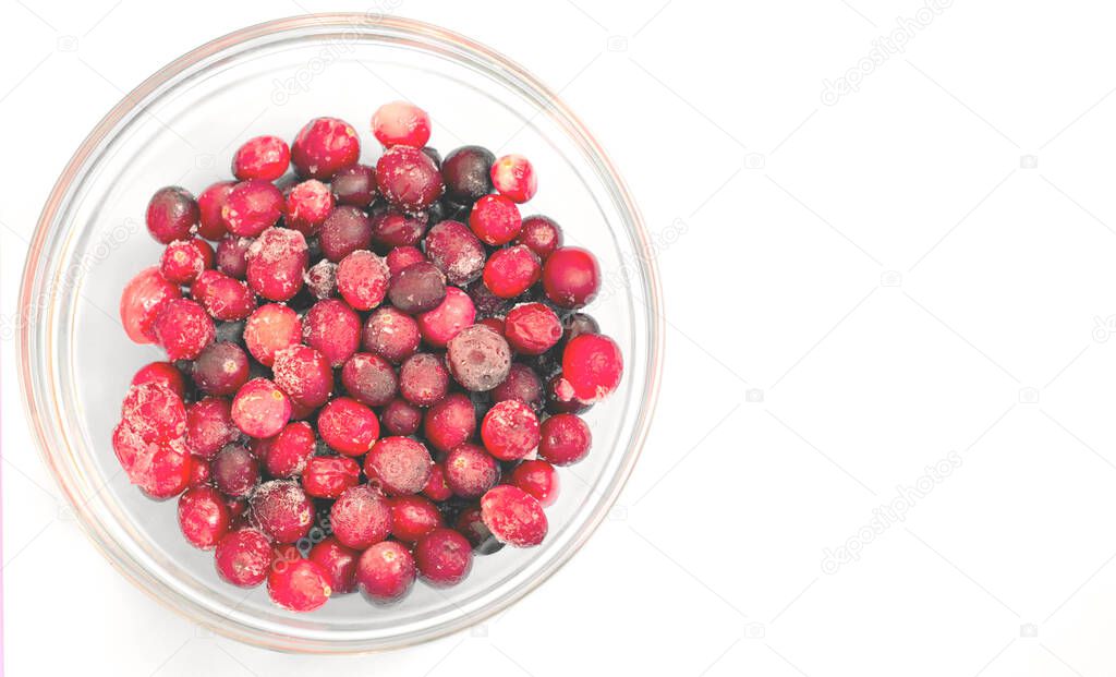 Frozen lingonberries in a glass plate on a light background.Flat lay.Copy space.