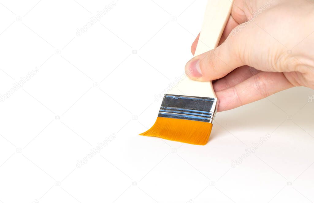 A man's hand holds paintbrush on a white background.Close-up. Copy space