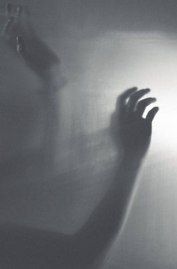 Odak dışında, buzlu film duvarının arkasında bir kadın eli var.