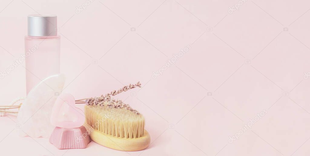 Body care products on a pink background. Gua sha, handmade soap, candle, wooden brush for body dry massage.Skin care products banner.