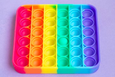 Yeni duyusal oyuncak - patlat onu, anti-stres konsepti. Gökkuşağı rengi, çukurluk ve dışbükey baloncuklar. Kapat. Üst görünüm