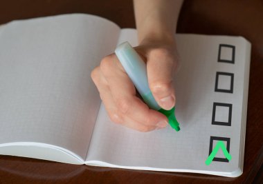 Not defterindeki kontrol listesinin alanındaki yeşil işaretleme. Kontrol listesi konsepti. İşaretleyici tutan bir el ve kopyalamak için alanı olan bir kontrol listesi.