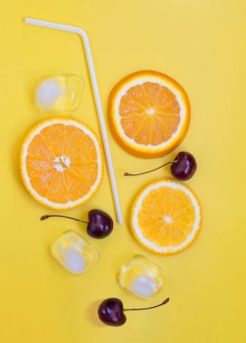 Summer background composition with orange slices, cherry and ice cubes. Lemonade drink concept. Flat lay on a yellow background. Vertical photo