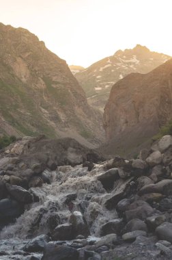 Gün batımında bir dağ nehrinin güzel manzarası. Buzuldan hızlı bir su akışı..