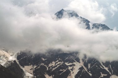Bulutların ve sislerin arasındaki dağ. Bulutlar kayalıkların arasında sürükleniyor. Sis ve anka ile karamsar manzara