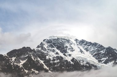 Bulutların ve sislerin arasındaki dağ. Bulutlar kayalıkların arasında sürükleniyor. Sis ve anka ile karamsar manzara