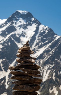 Taşların dengesi. Kayanın tepesinde taşları dengelemek. Kapatın. Mavi gökyüzünde taşların dengesi ve arka planda bir kopya alanı olan dağlar. Taşlar dengede, sürdürülebilirlik kavramı. Kapat.
