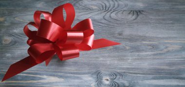 red ribbon bow on wooden gray background