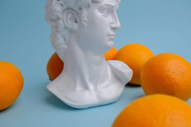 mavi arkaplanda portakallar ve heykel.