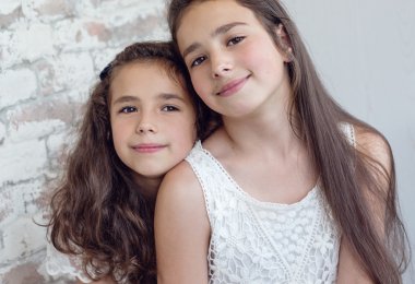 İki sevimli küçük kız kardeşi araya sokulmuş 