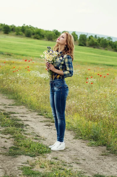 フィールドのヒナギクの花束を持つ若い女性 — ストック写真