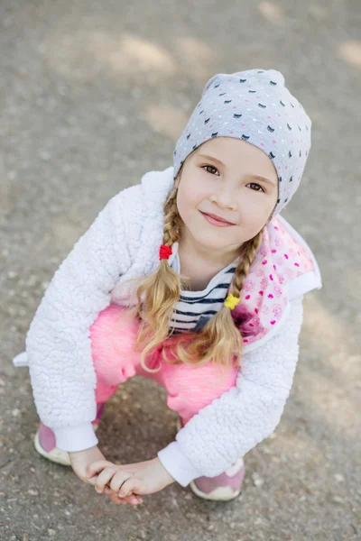 Glückliches kleines Mädchen sitzt auf seinen Hinterbeinen — Stockfoto