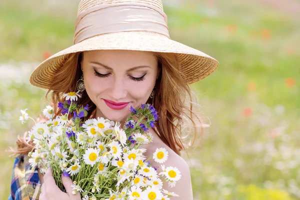 フィールドのヒナギクの花束を持つ若い女性 ストックフォト