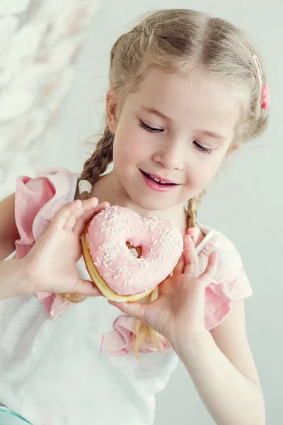Щаслива маленька дівчинка їсть пончик — стокове фото