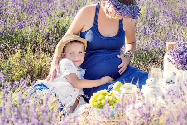 Glückliches kleines Kind umarmt eine schwangere Mutter — Stockfoto