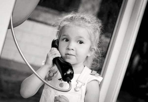 Toddler girl talking by the city phone — Stock Photo, Image