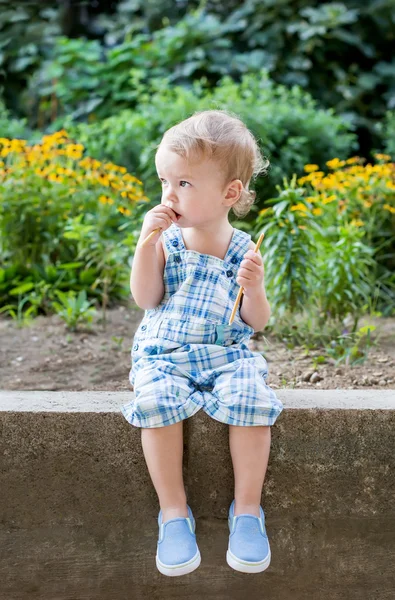 Lindo niño comiendo dulce paja sentado — Foto de Stock