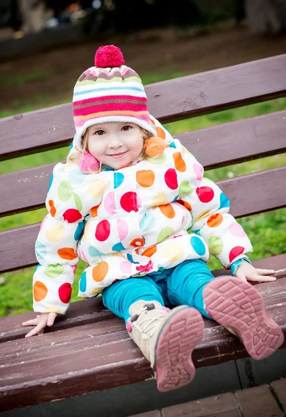 Linda niña pequeña sentada en el banco —  Fotos de Stock