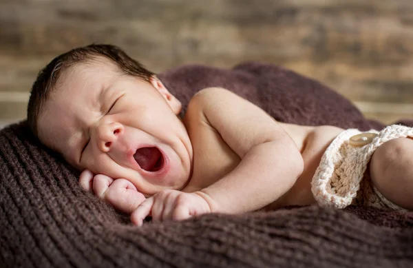 Cute newborn yawns lying on a blanket — Stock Photo, Image