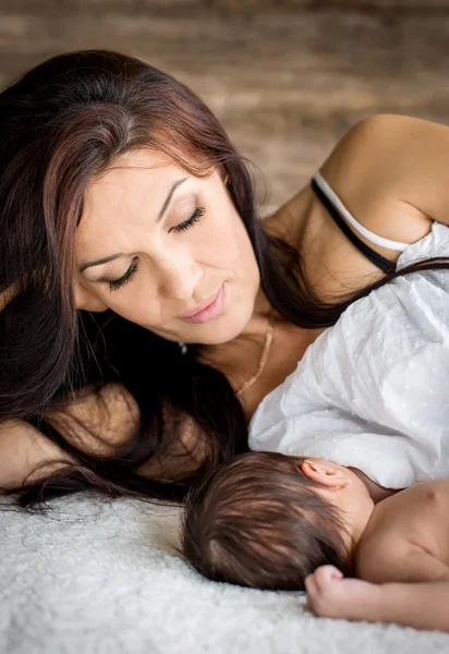 Красивая мать с новорожденным лежачим ребенком — стоковое фото