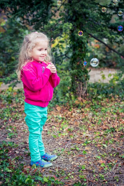 Funny cute girl admires soap bubbles — Stock Photo, Image