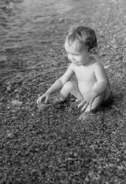 Glada barnet pojke spelar på havet — Stockfoto