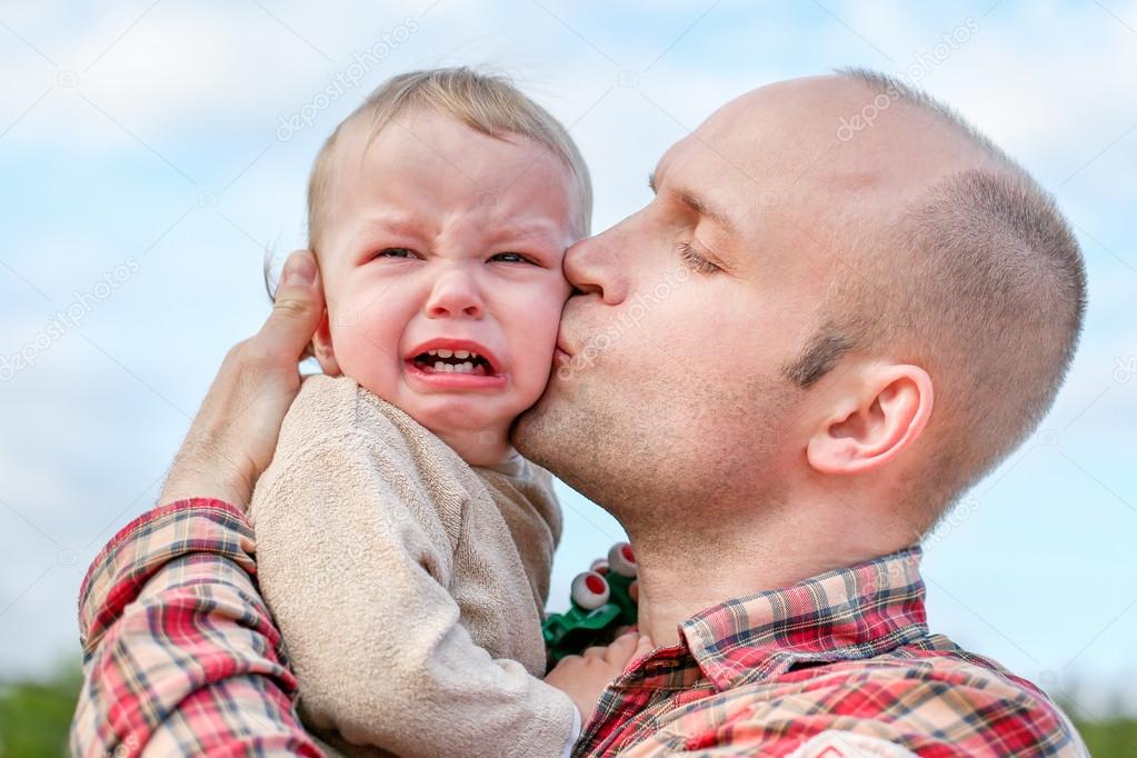 caring father calms toddler son outdoors 