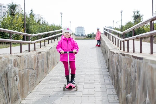 Bir parkta bir scooter üzerinde mutlu küçük kız — Stok fotoğraf