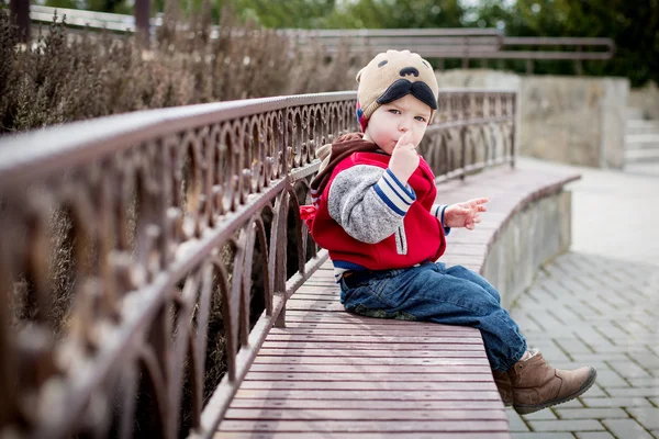 Niño sentado en un banco. — Foto de Stock