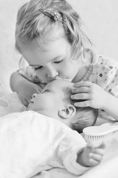 Милая сестренка Тоддлер целует новорожденного — стоковое фото
