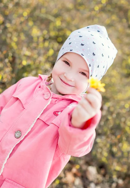 Glückliches kleines Mädchen mit einer gelben Blume — Stockfoto