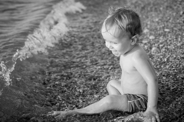 Menino feliz brincando no mar — Fotografia de Stock